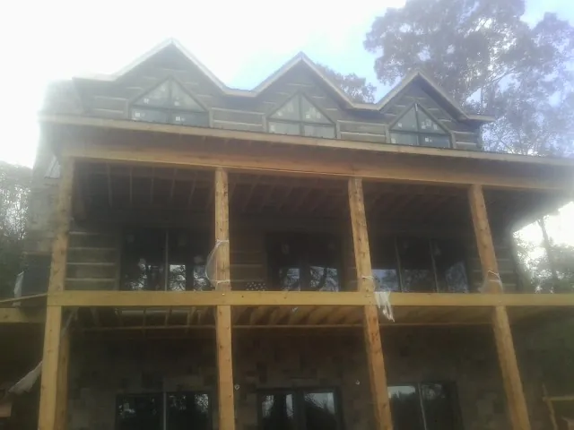 Dormers and porch framing on a large log home under construction — Roof Coating work by our crew in Exline