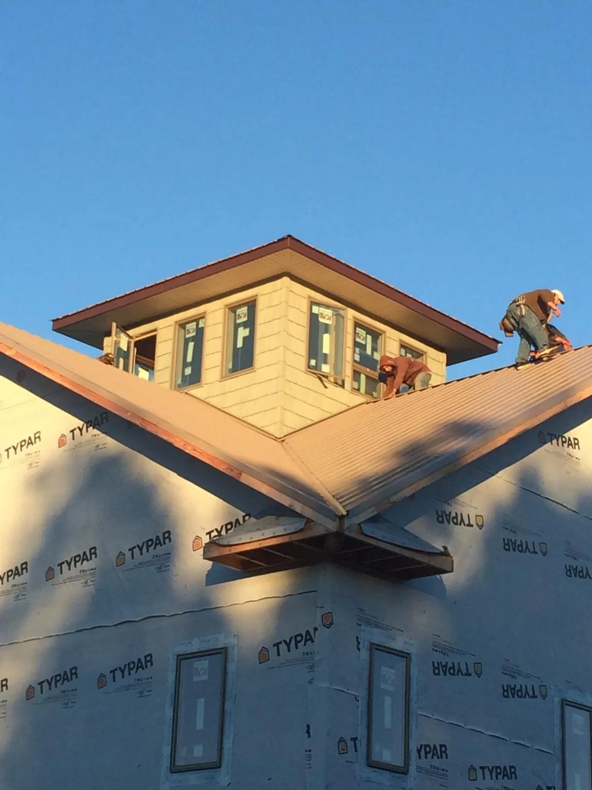 Roofers working around a rooftop cupola on a new metal roof at sunset — Roof Waterproofing in Exline by Roofing Brothers